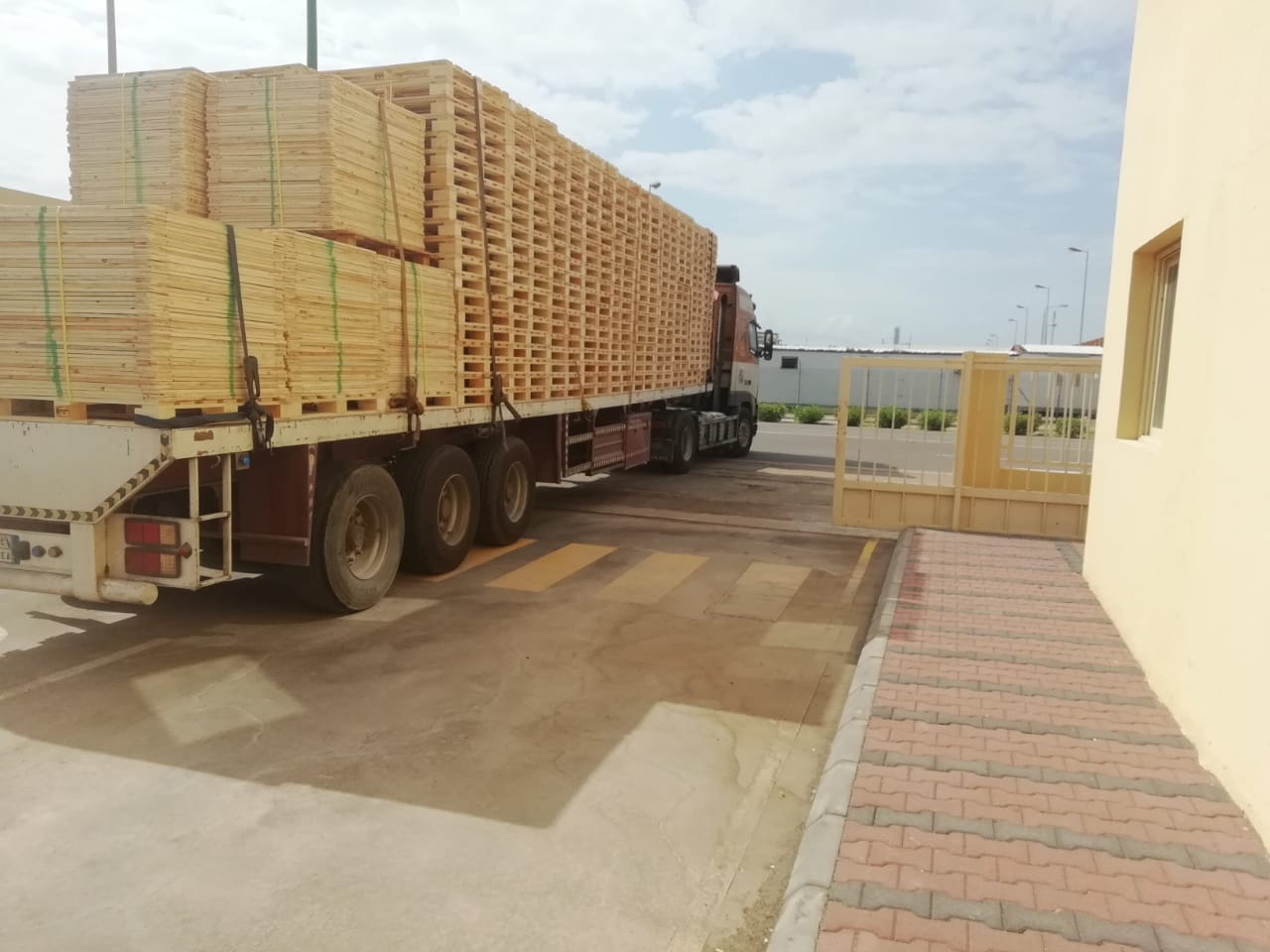 Export Pallet Shipping and Logistics Flatbed trailer truck loaded with stacked wooden pallets leaving the Export Pallets facility in Yanbu, KSA